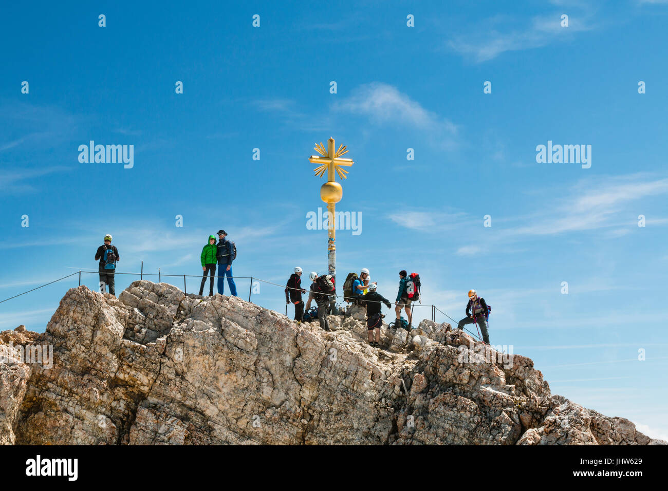GARMISCH - JULY 04: Summit of the Zugspitze, Germany with some tourists around the golden cross on July 04, 2016. Stock Photo