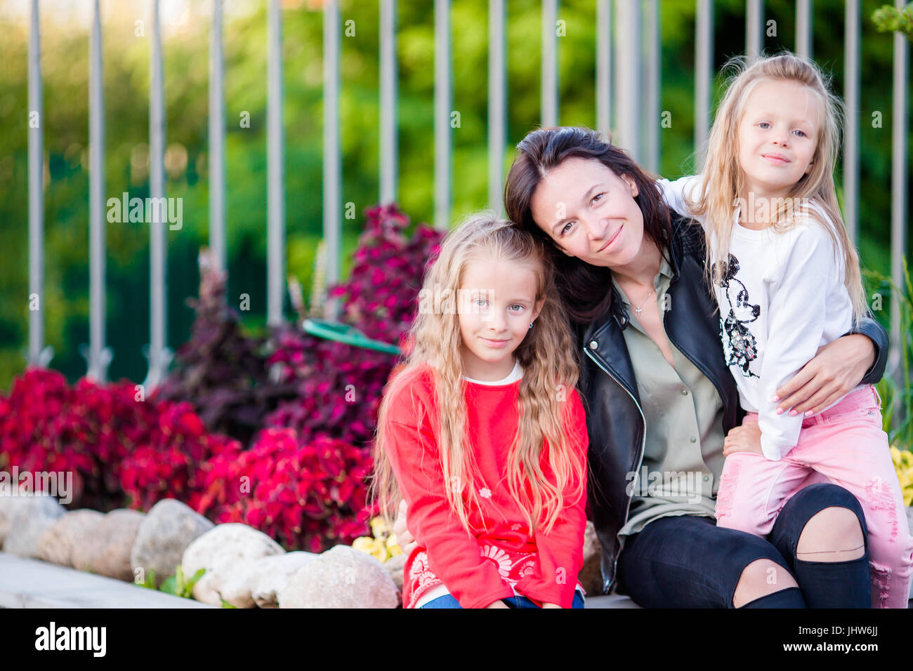 Adorable little girls with young mother in garden Stock Photo - Alamy