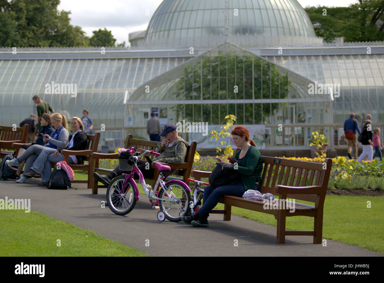 Botanic Gardens Glasgow sunny day family with bike outside greenhouse on bench Stock Photo