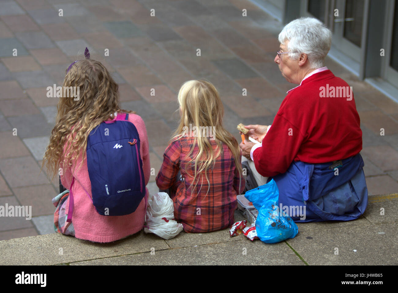 white granny and grandchildren sitting on the steps eating  lunch at the royal concert hall Glasgow Stock Photo