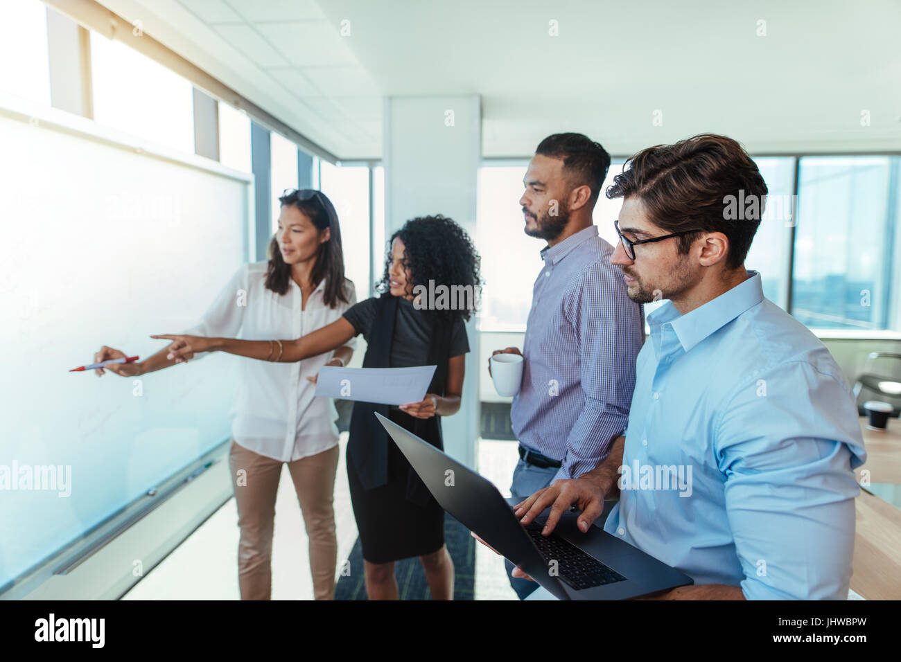 Women entrepreneurs discussing business ideas in boardroom with their colleagues. Young business investors presenting a business plan on a white board Stock Photo