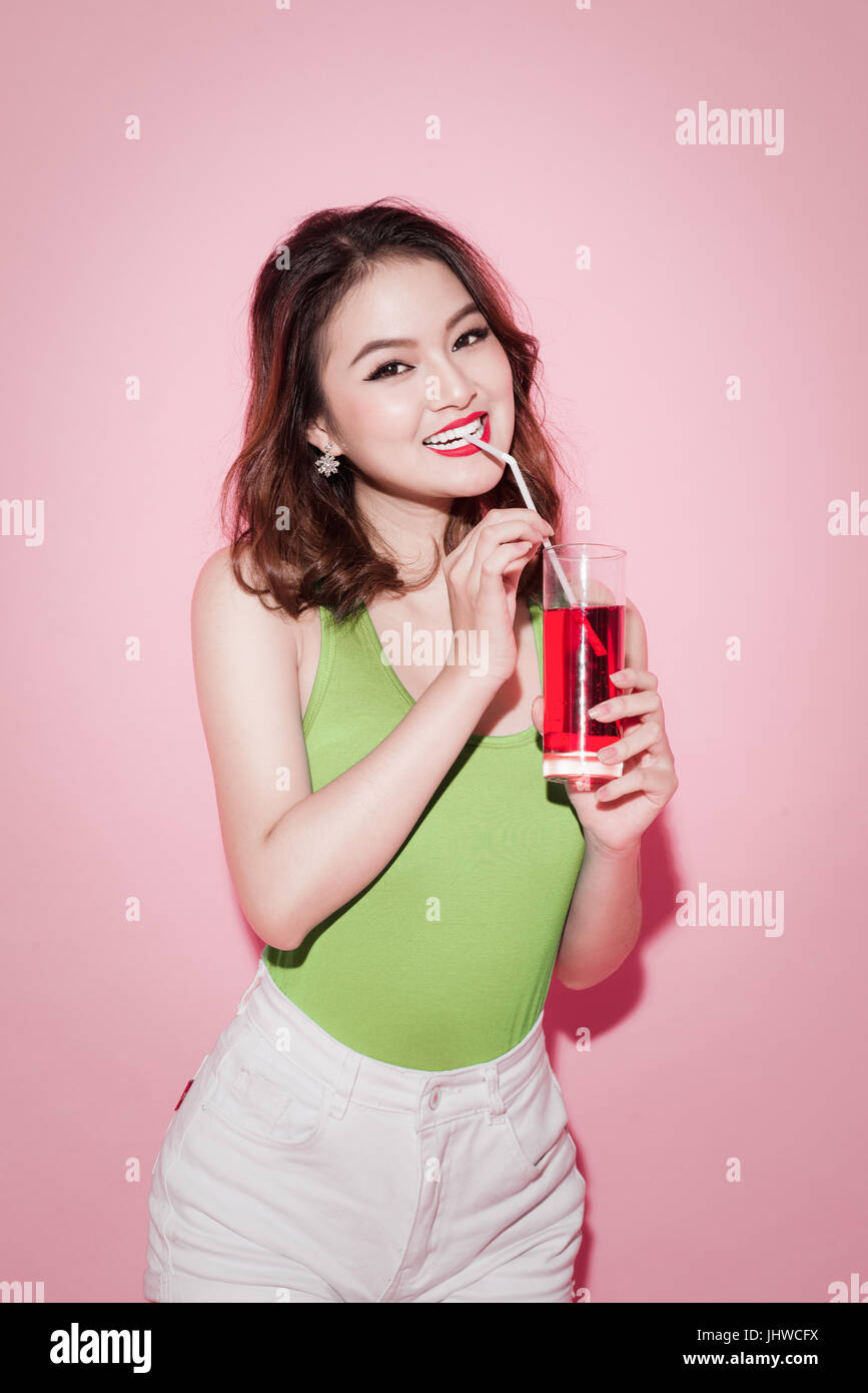 Celebrating asian woman drinking red softdrink Stock Photo