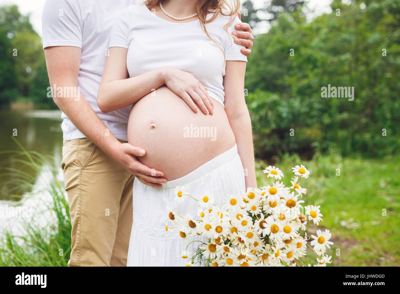 Pregnant couple with chamomile bouquet in a park Stock Photo Alamy