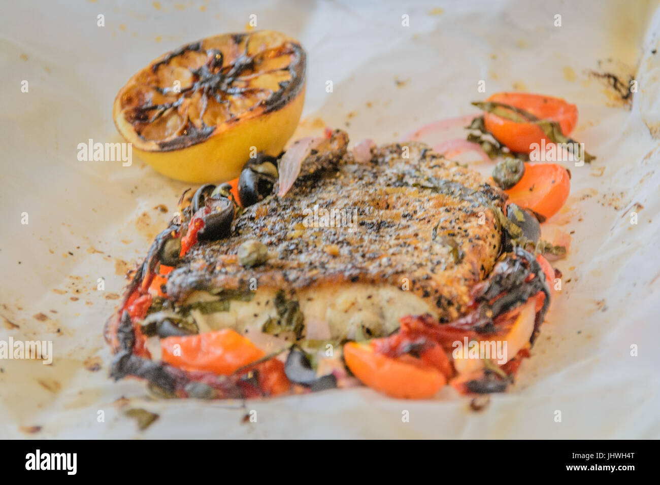 Sea bass Al Cartoccio fresh sea bass fillet cooked in parchment paper with sundried tomatoes, anchovies and capers Stock Photo