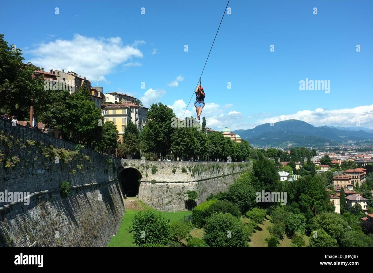 A person zip wiring alongside the historic walls of the Citta Alta (upper city), Bergamo, Lombardy, northern Italy, July 2017 Stock Photo