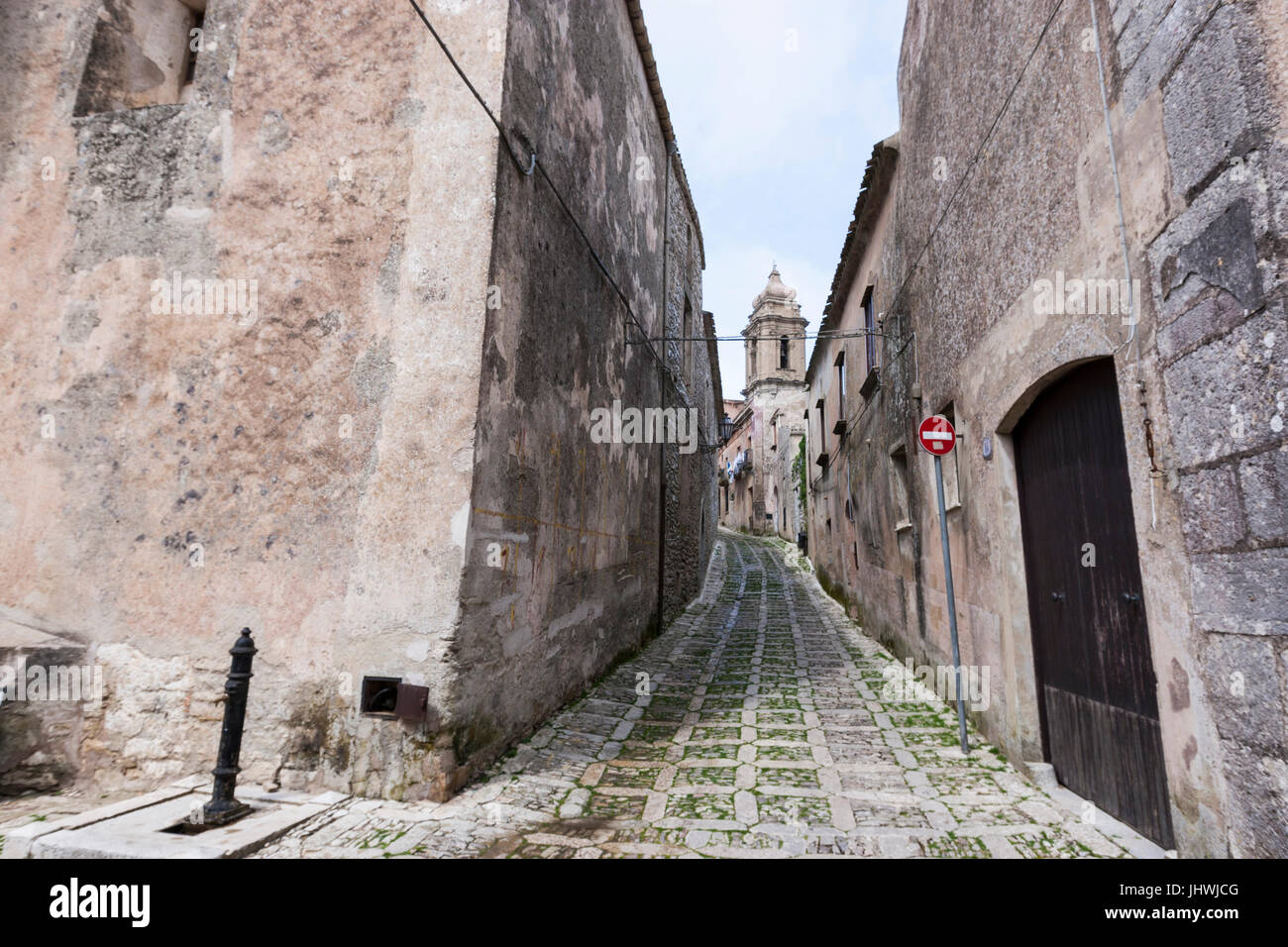 Narrow street with stone houses and church hires stock photography and