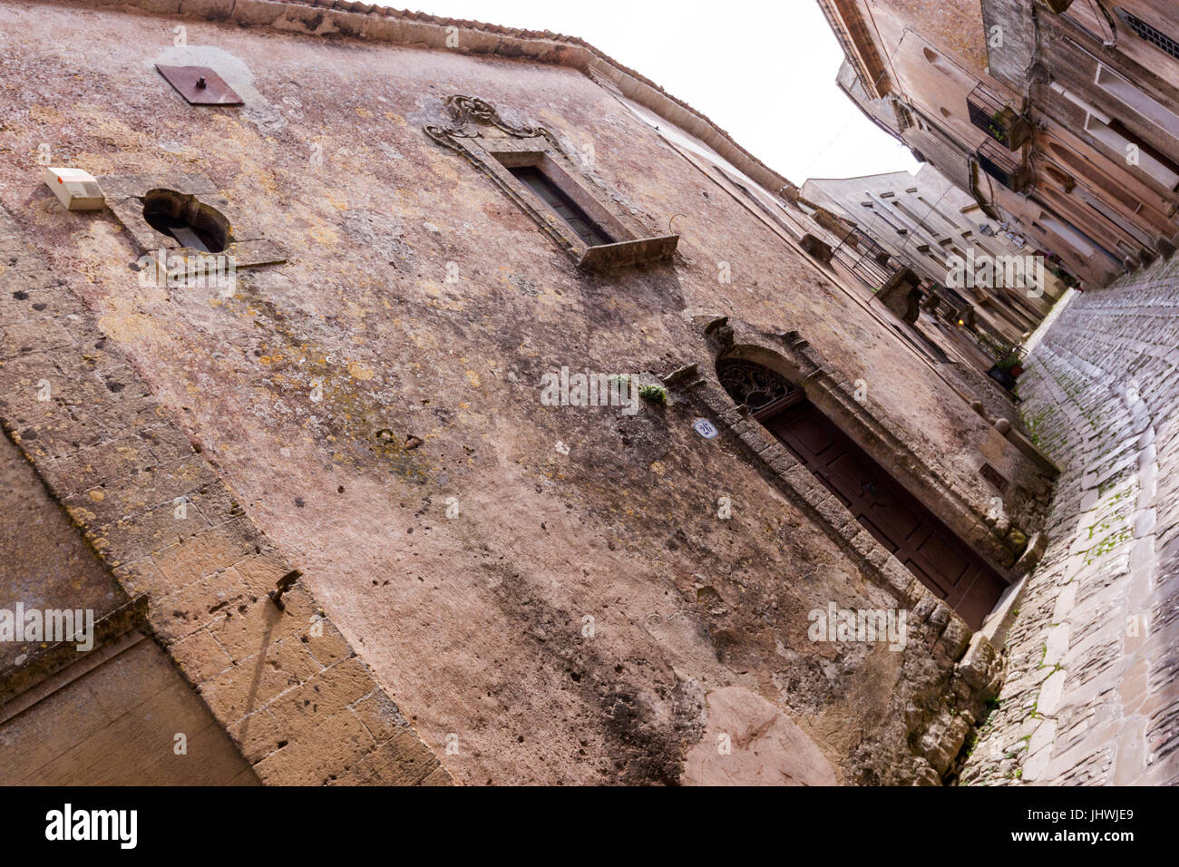 Narrow street with stone houses and church in Erice, Sicily, Italy
