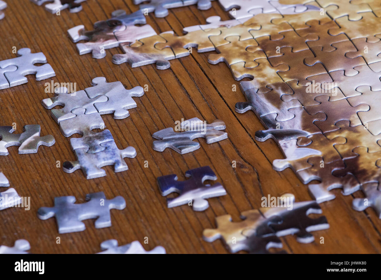 Scattered pieces of jigsaw puzzle on wooden table. Effort to fit thing