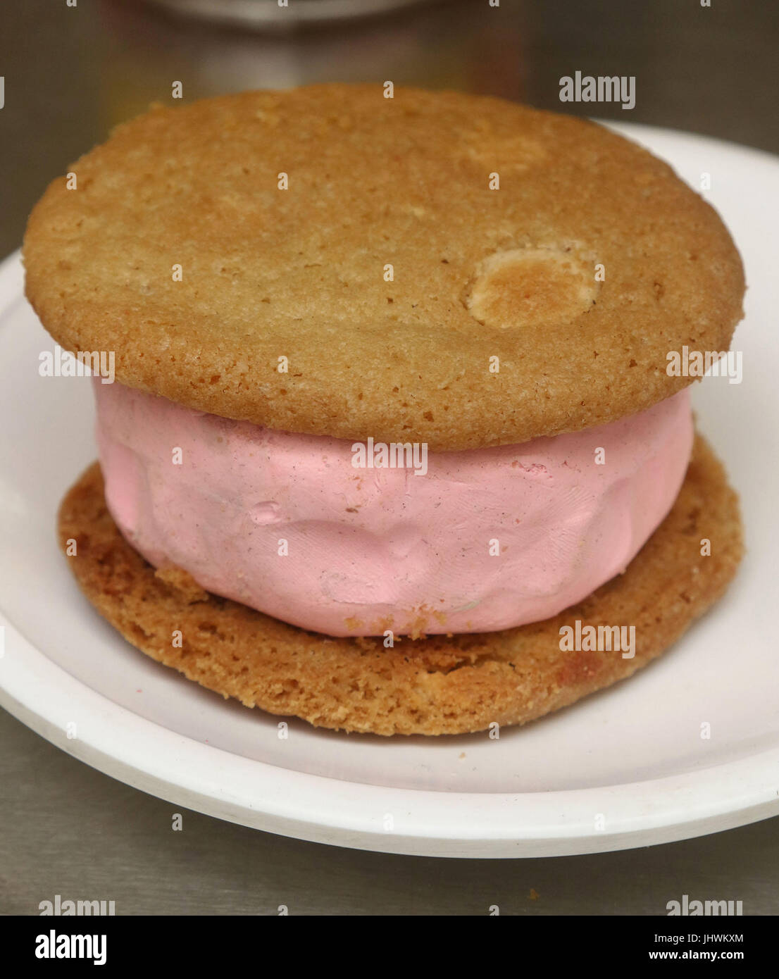 Strawberry ice cream sandwich made with two vanilla cookies and