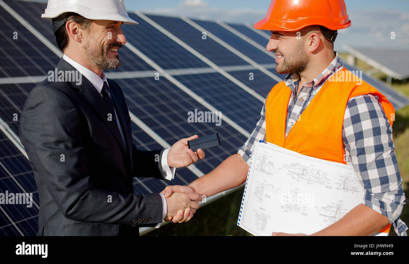 At solar energy station business client and foreman shaking hands. Stock Photo