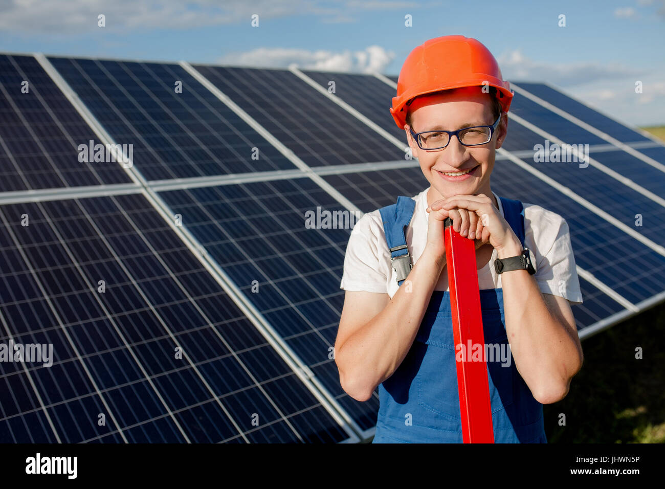 Young worker standing at solar energy station in the field. Stock Photo