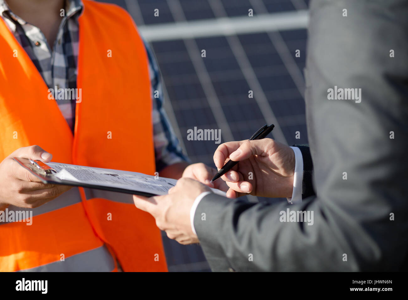 Close up view on foreman and client sigining contract at solar power station. Stock Photo