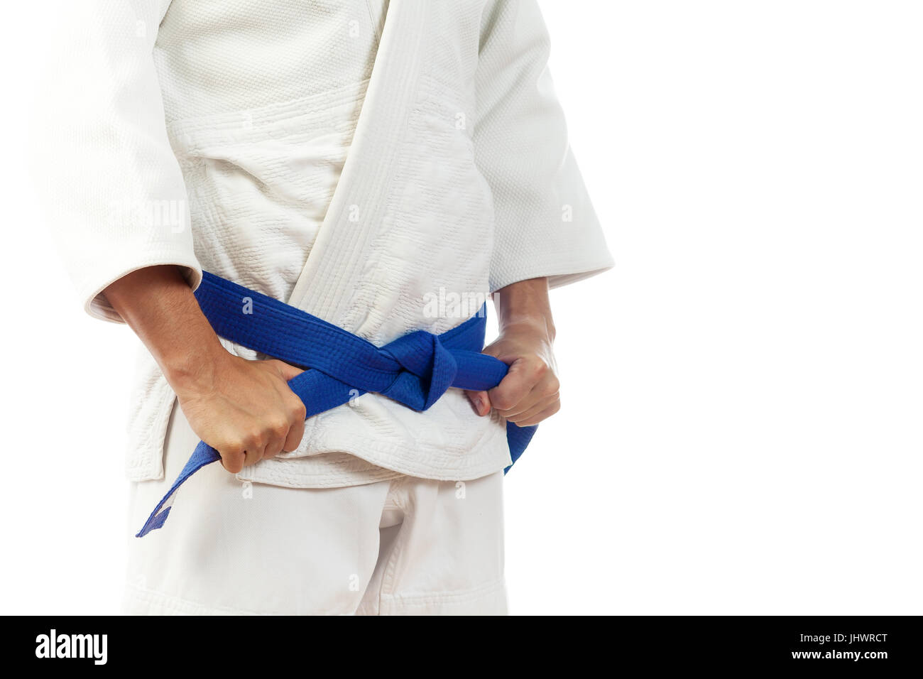 Close-up of a man fighter in a white kimono for judo, Jiu Jitsu ties up a  blue belt on an isolated white background Stock Photo - Alamy