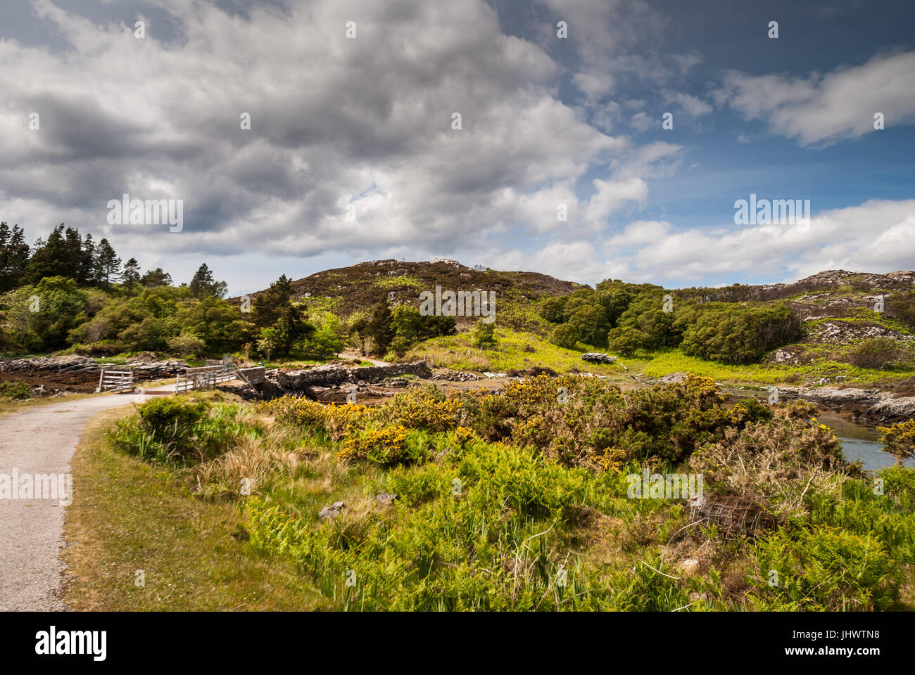 Assynt Peninsula, Scotland - June 7, 2012: Short stone bridge over creek landing into Atlantic Ocean inlet South of Loch An Arbhair under heavy sky. F Stock Photo