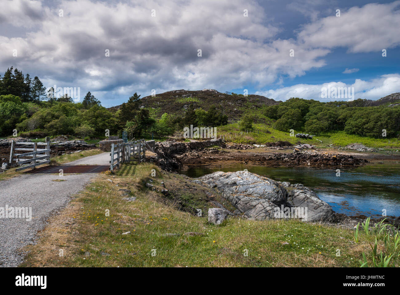 Assynt Peninsula, Scotland - June 7, 2012: Short stone bridge with cattle grill over creek landing into Atlantic Ocean inlet South of Loch An Arbhair  Stock Photo