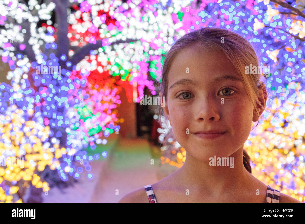 Smiling young Caucasian girl with bright lights in tress behind her Stock Photo