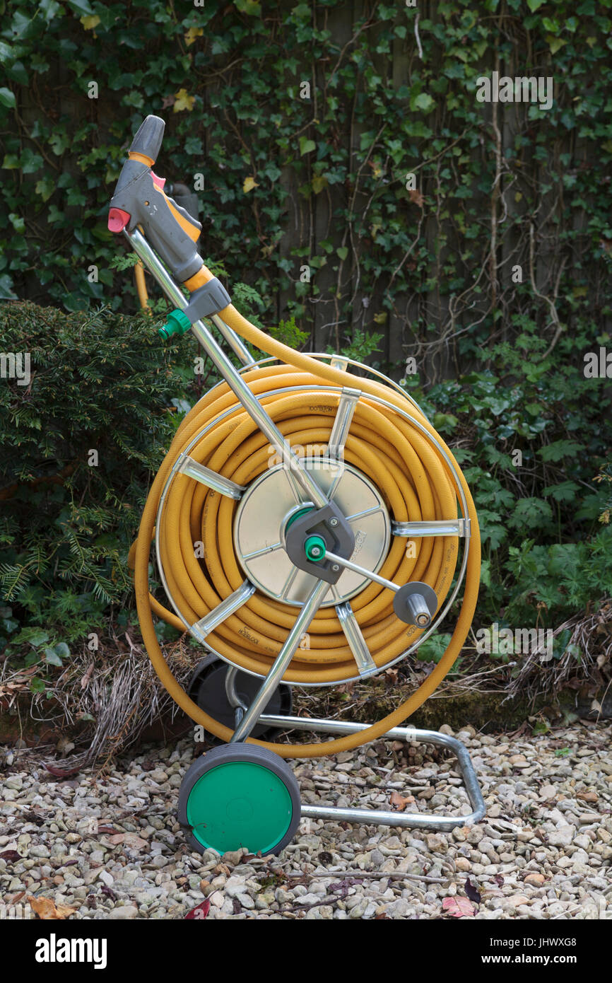 Yellow Hosepipe on a Reel in a garden with green backdrop Stock Photo