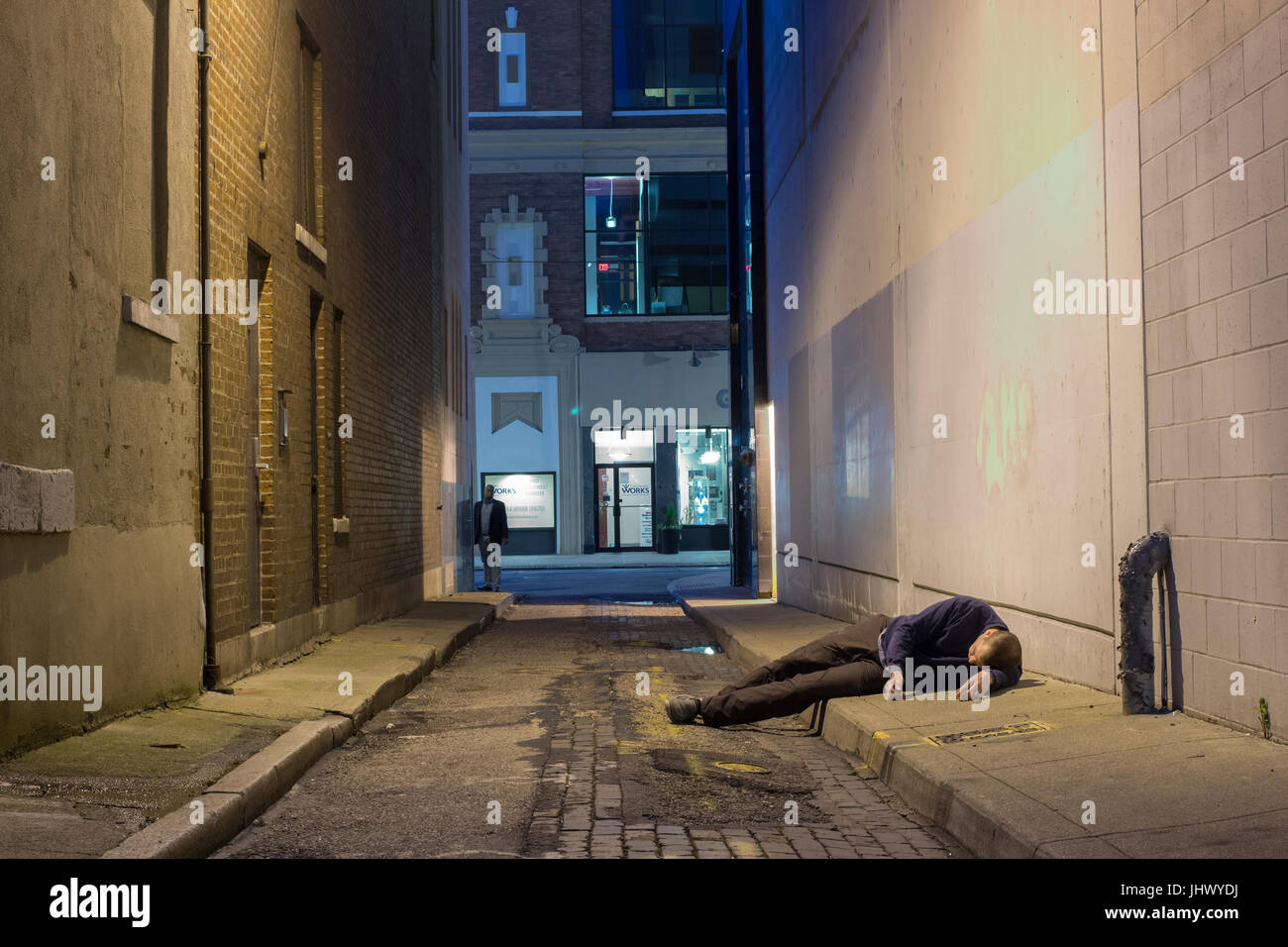 Man in a dark alley appears to be drunk, lost or needs help. Stock Photo