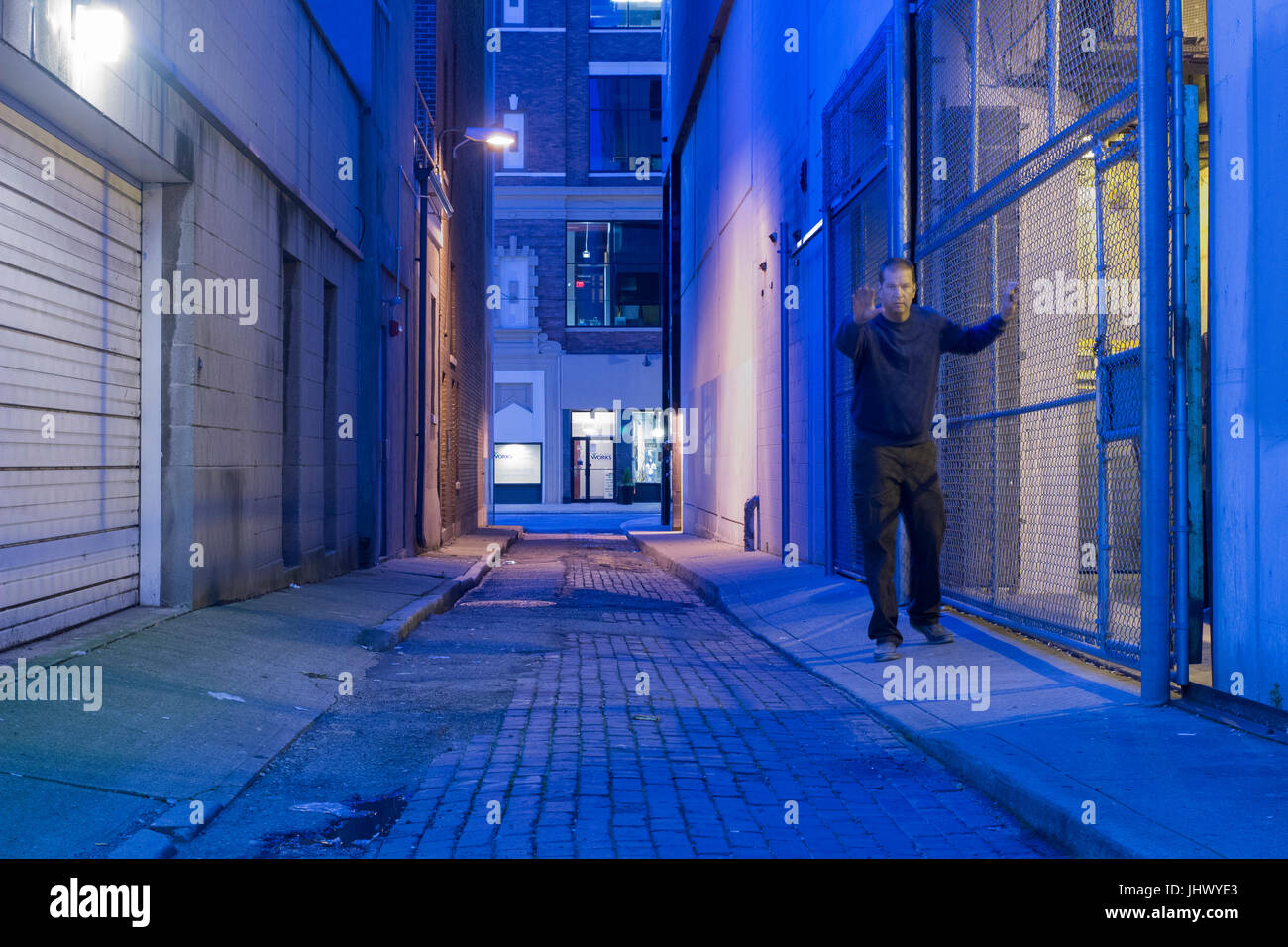 Man in a dark alley appears to be drunk, lost or needs help. Stock Photo