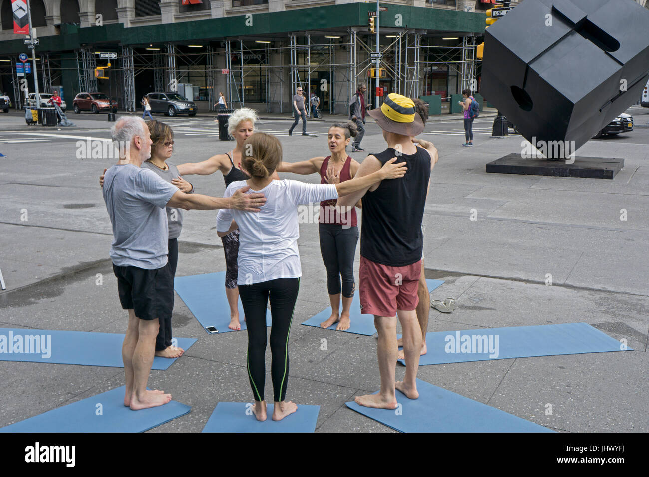 At the conclusion of an outdoor free yoga class the instructor (maroon top) leads the group in a moment of thought & prayer. On Astor Place in NYC Stock Photo