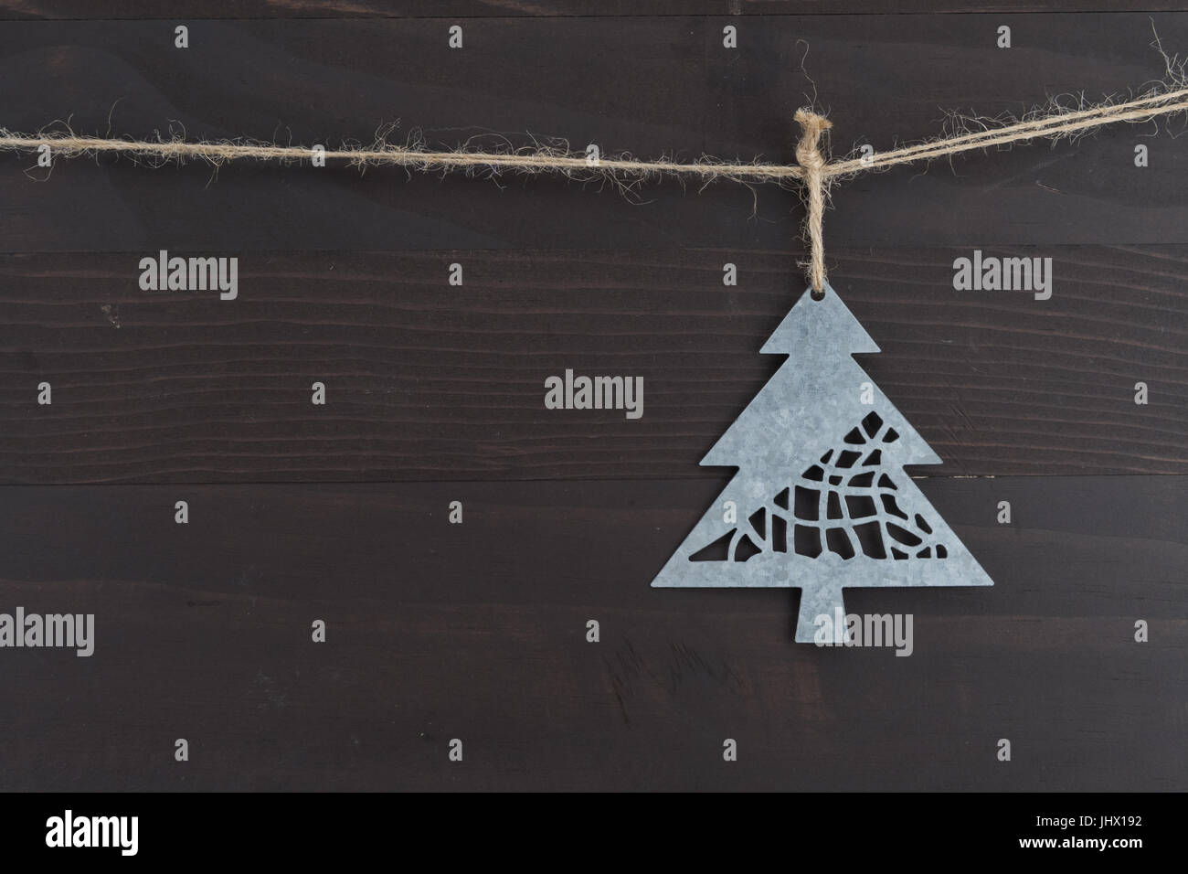 Close Up of Metal Pine Tree Ornament against dark wood background Stock Photo