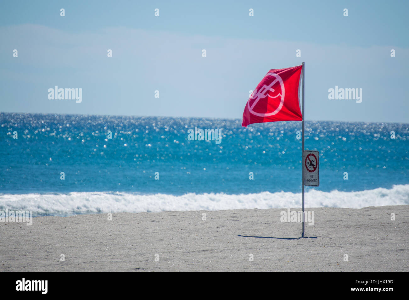 red 'No Swimming' warning flag and sign on a Florida beach Stock Photo