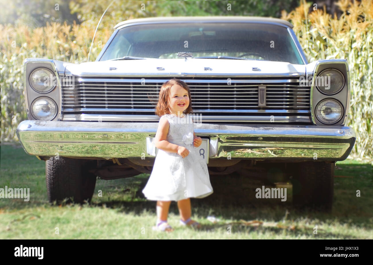 Girl in dress standing in front of classic car Stock Photo