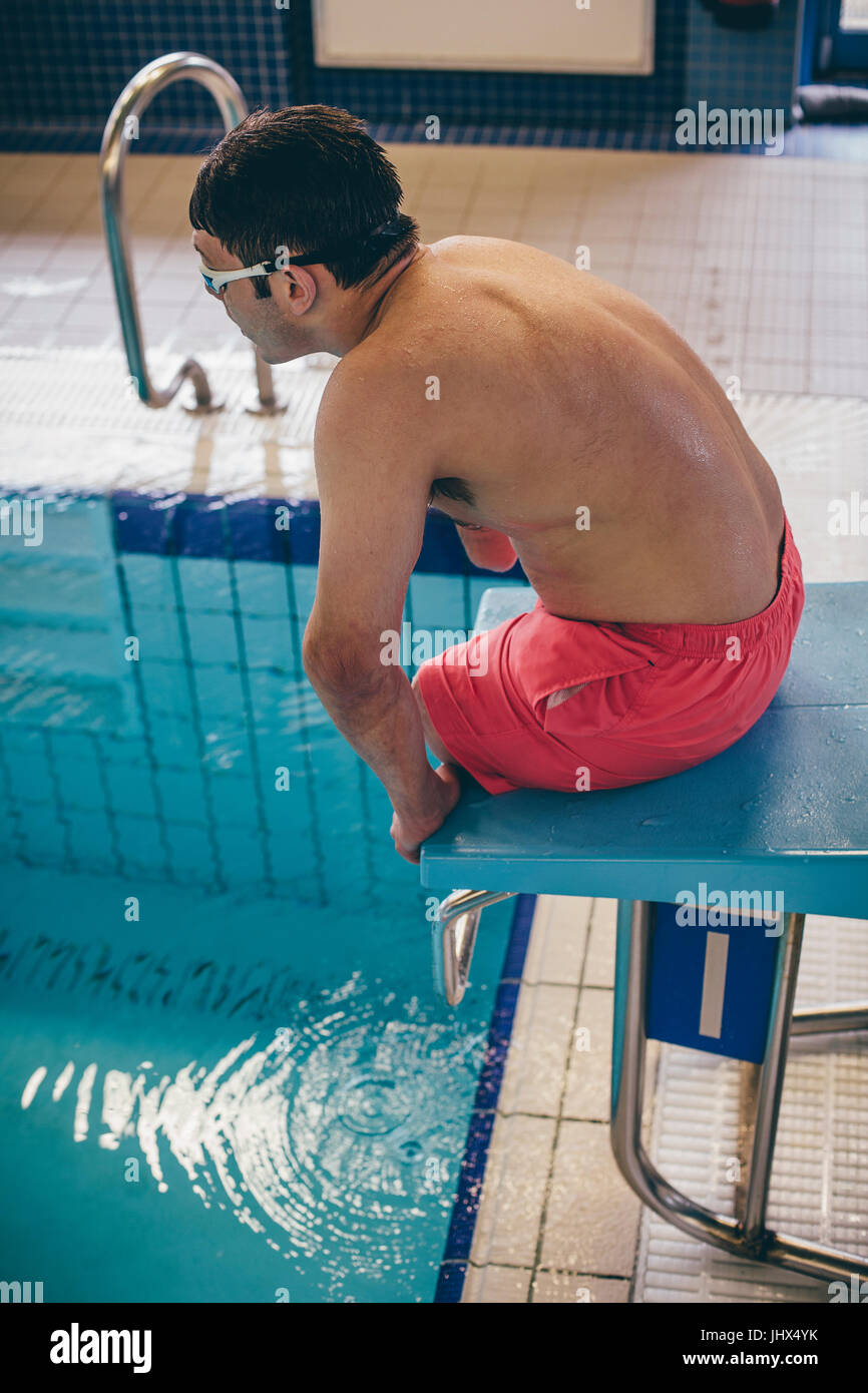Quadriplegic swimmer ready to dive in. He is sitting on the platform with goggles on. Stock Photo