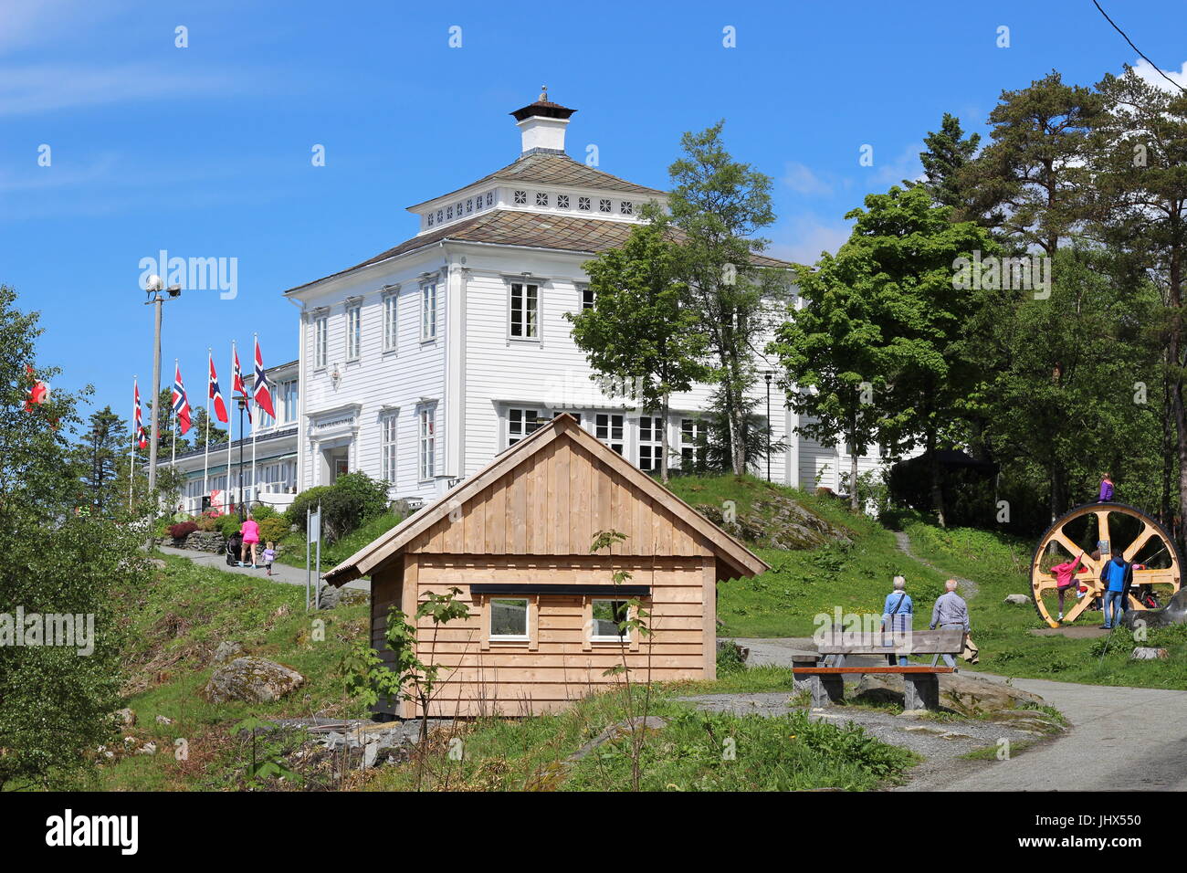 Walkers on woodland path to hill summit with wooden cabin and children playing Stock Photo