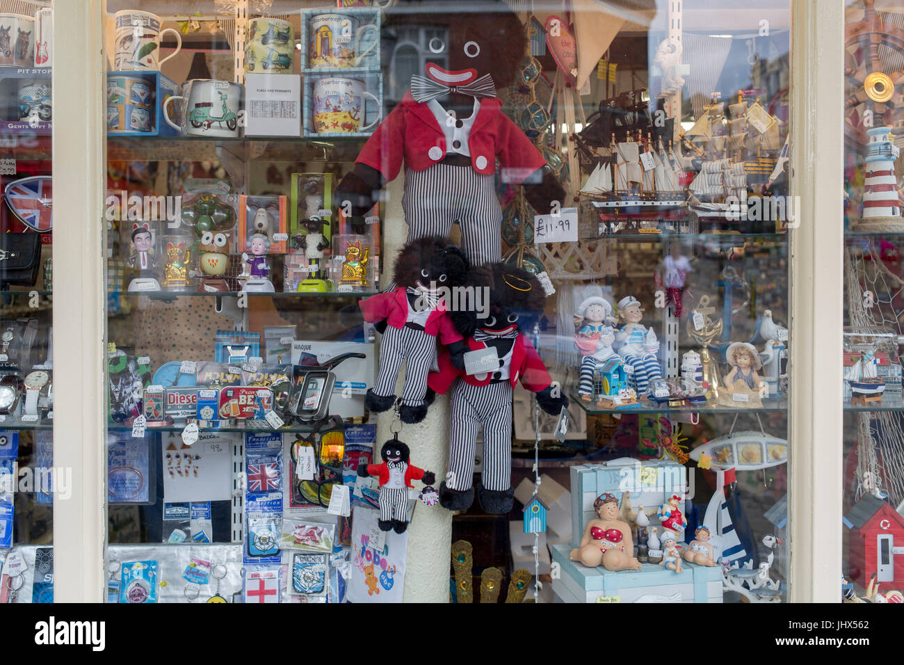 Detail of a shop window selling seaside holiday trinkets including different sizes of Golliwogs, on 14th July 2017, at Scarborough, North Yorkshire, England. The golliwog is a black fictional character from the late 19th century depicting a rag doll. It was reproduced by commercial and hobby toy-makers as a children's toy and had great popularity in the UK and Australia into the 1970s. The doll has black skin, eyes rimmed in white, clown lips and frizzy hair and was seen, along with the teddy bear, as a suitable soft toy for a young boy. The image of the doll has become the subject of controve Stock Photo