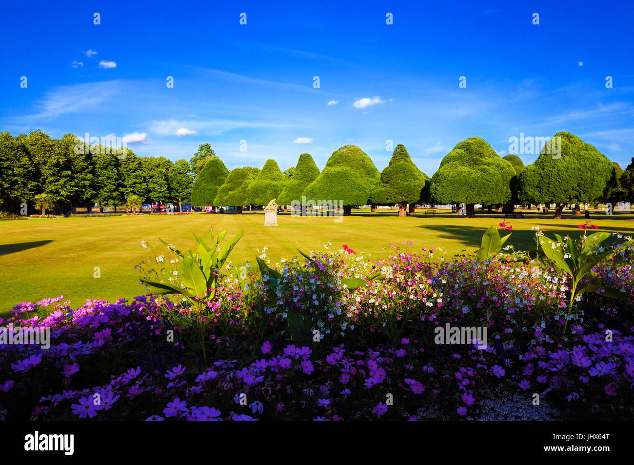 A perfect summer's evening at Hampton Court Palace showing the East Front Gardens with its beautiful herbaceous borders and famous ancient yew trees. Stock Photo