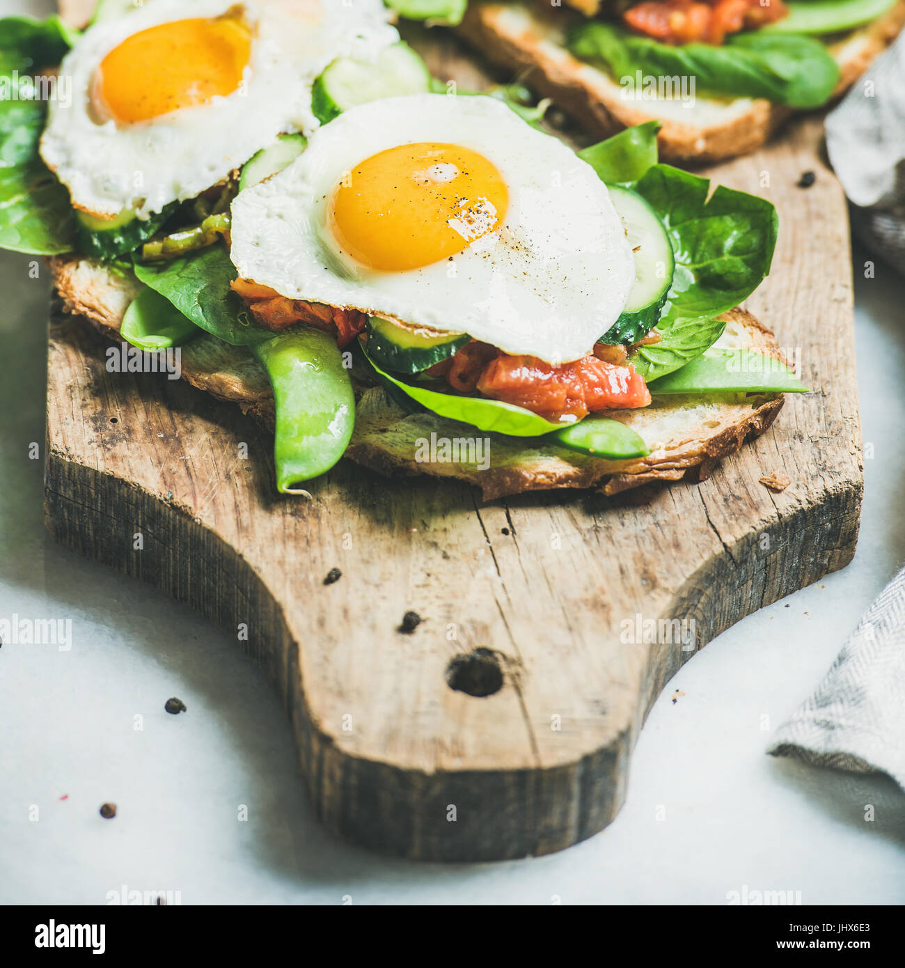 Bread toasts with fried eggs and fresh vegetables, square crop Stock Photo
