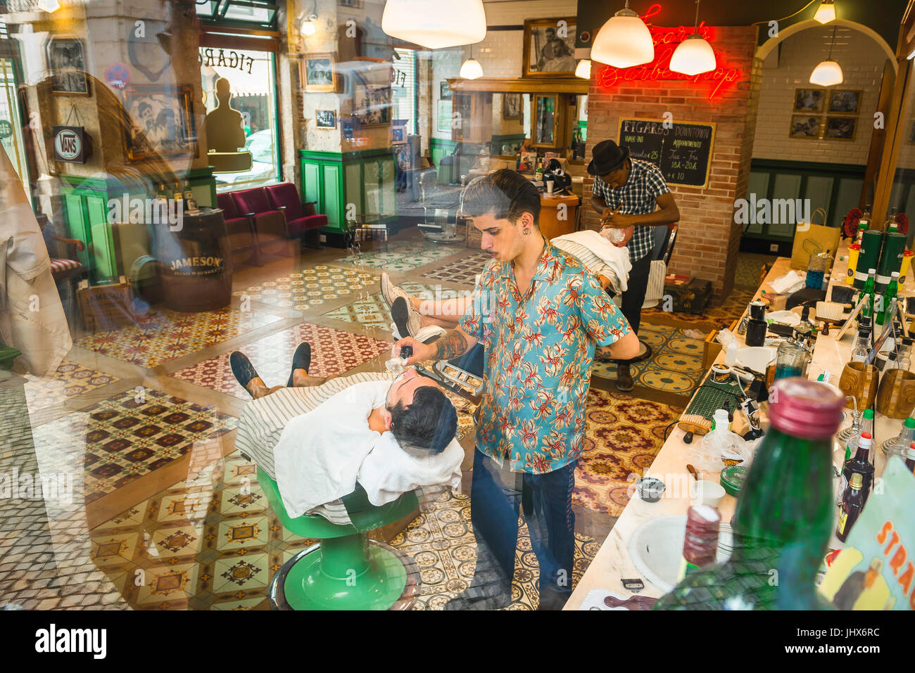 Barber shop, view through plate glass window of men being shaved in Figaro's traditional barber shop in the Baixa district of Lisbon, Portugal. Stock Photo