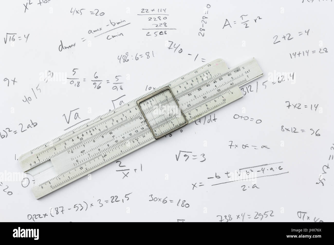 Slide rule lying on a piece of paper with handwritten calculations