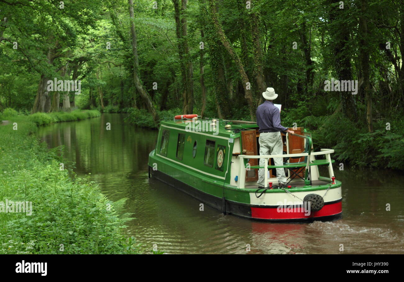 Narrowboat holiday makers navigate the Monmounthshire and Brecon Canal near Llangynidr in the Brecon Beacons, Powys, South Wales, UK - summer Stock Photo