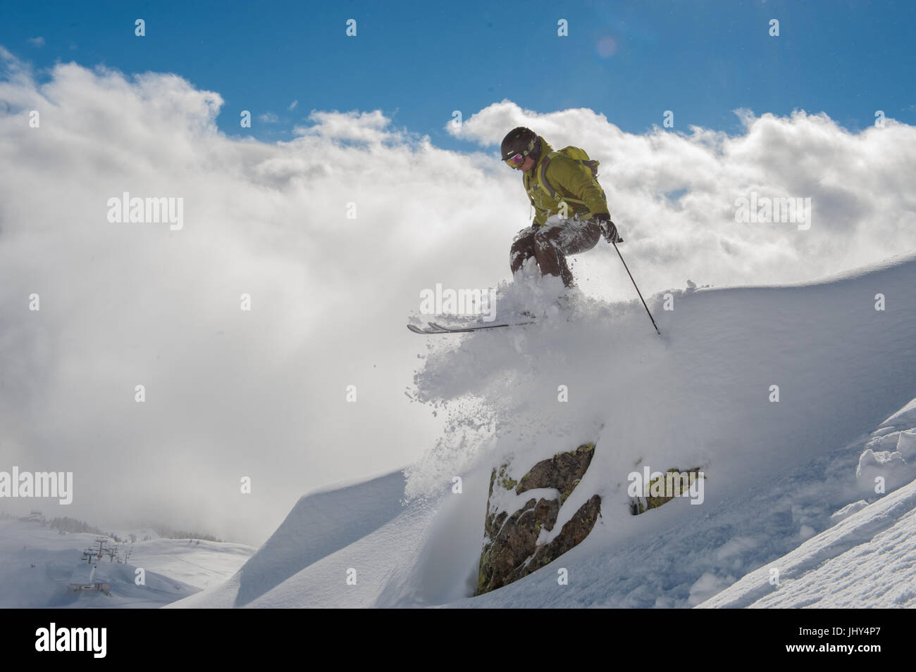 Skier jumping over a rock with clouds in the background Stock Photo - Alamy