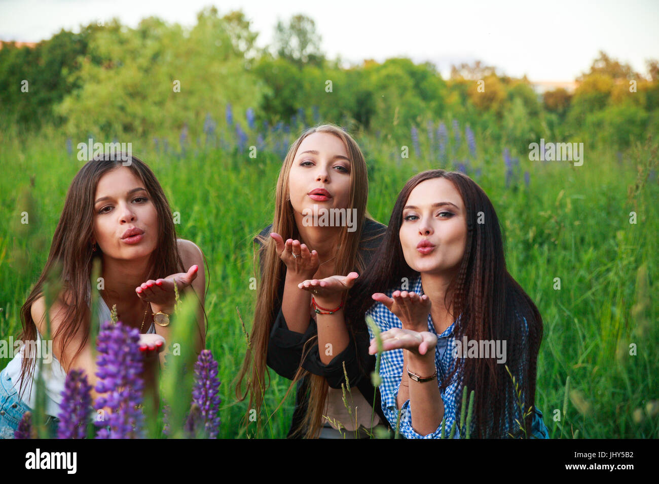Three beautiful young happy girls best friends send an air kiss , smiling and laughing Stock Photo