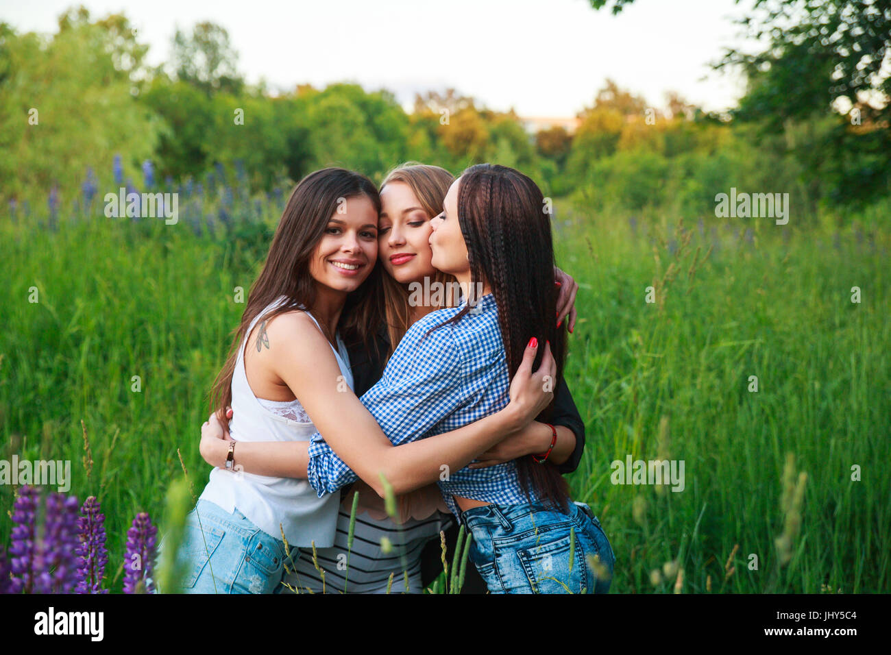 Girlfriends Friendship Happiness Community Concept. Three smiling friends hugging outdoors in the nature Stock Photo