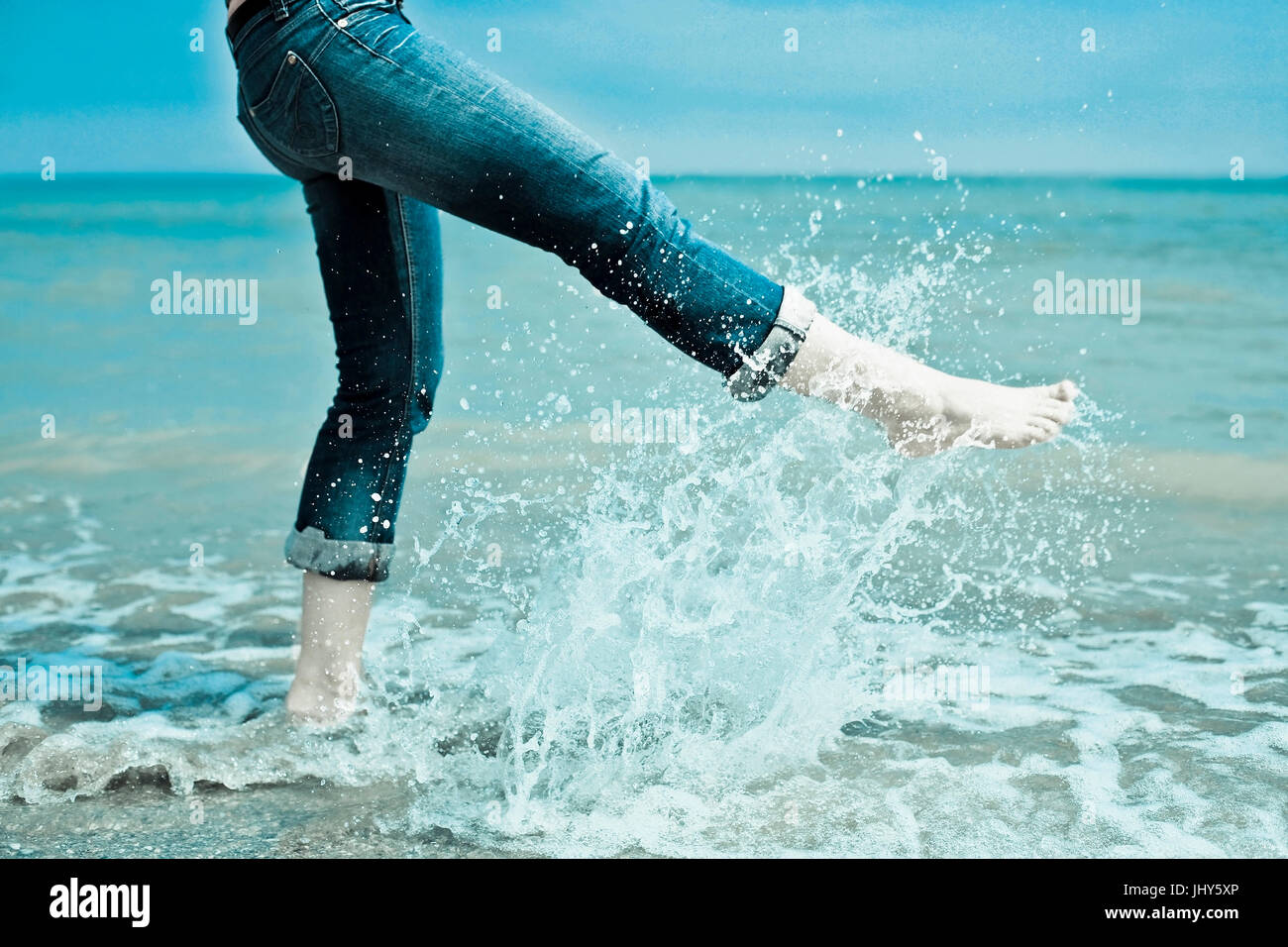 Young woman bathes her feet in the sea, Junge Frau badet ihre Fuesse im Meer Stock Photo