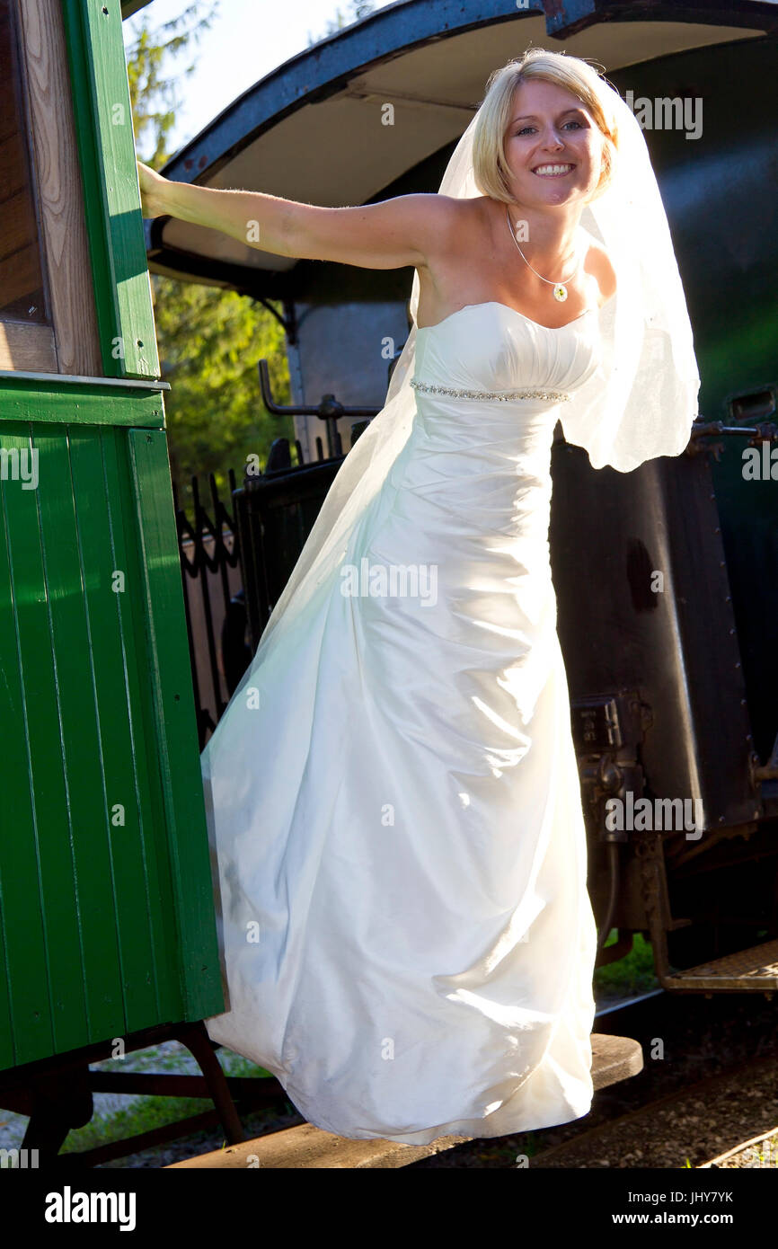 happy bride stands on an old Lokomitive - happily bride standing on in old railway locomitive, gl¸ckliche Braut steht auf einer alten Lokomitive - hap Stock Photo