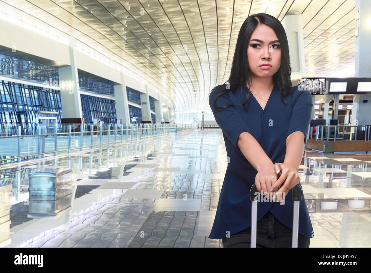 Pretty asian traveler with suitcase waiting in the airport terminal Stock Photo