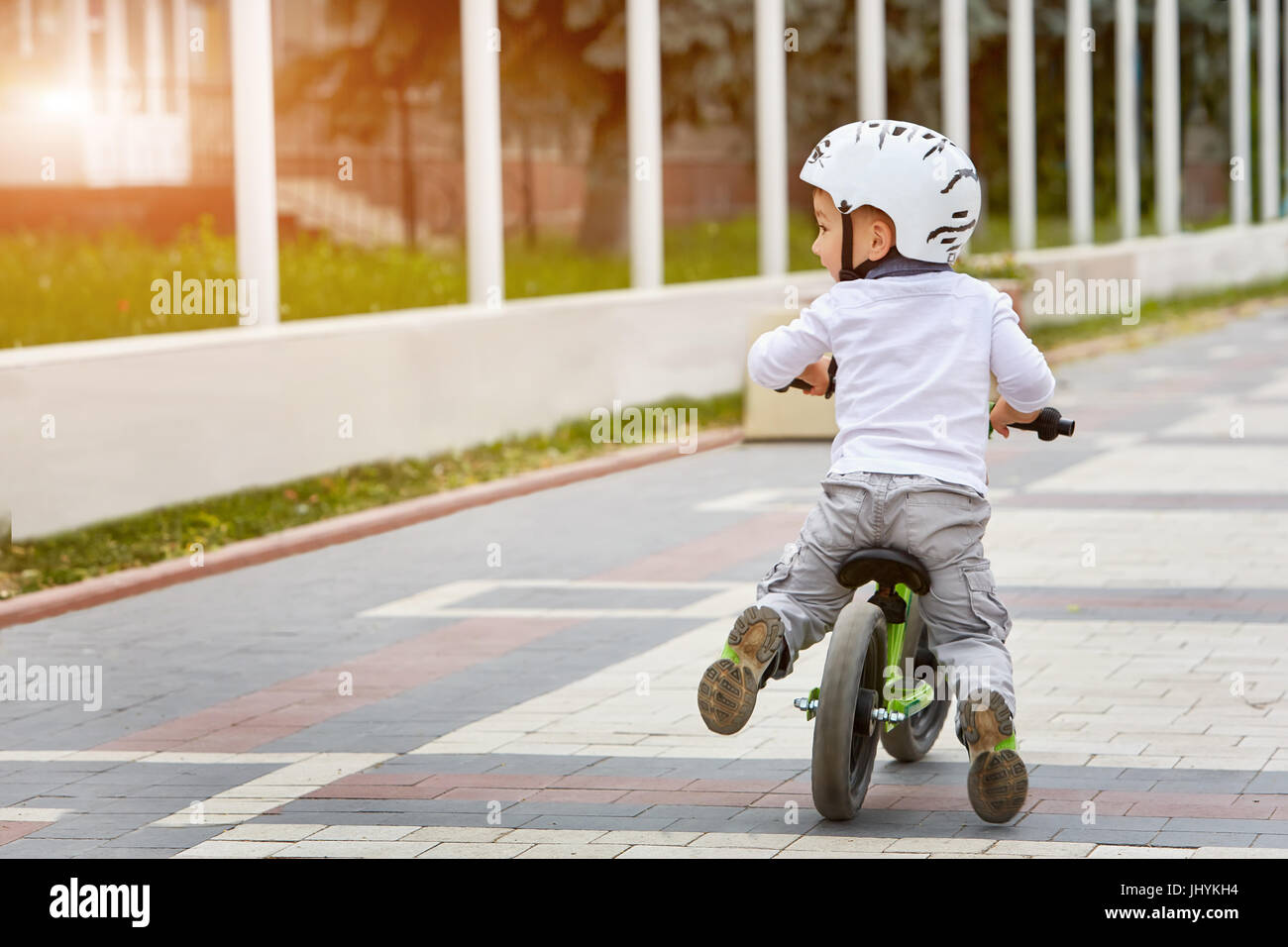 Little boy kid in helmet ride a bike in city park. Cheerful child