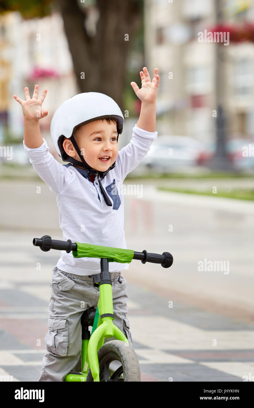 Little boy kid in helmet ride a bike in city park. Cheerful child