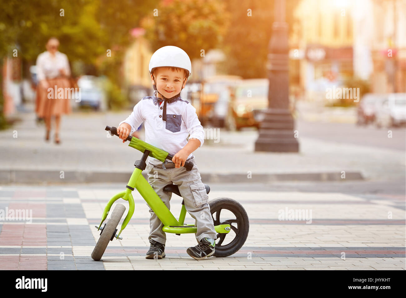 Little boy kid in helmet ride a bike in city park. Cheerful child