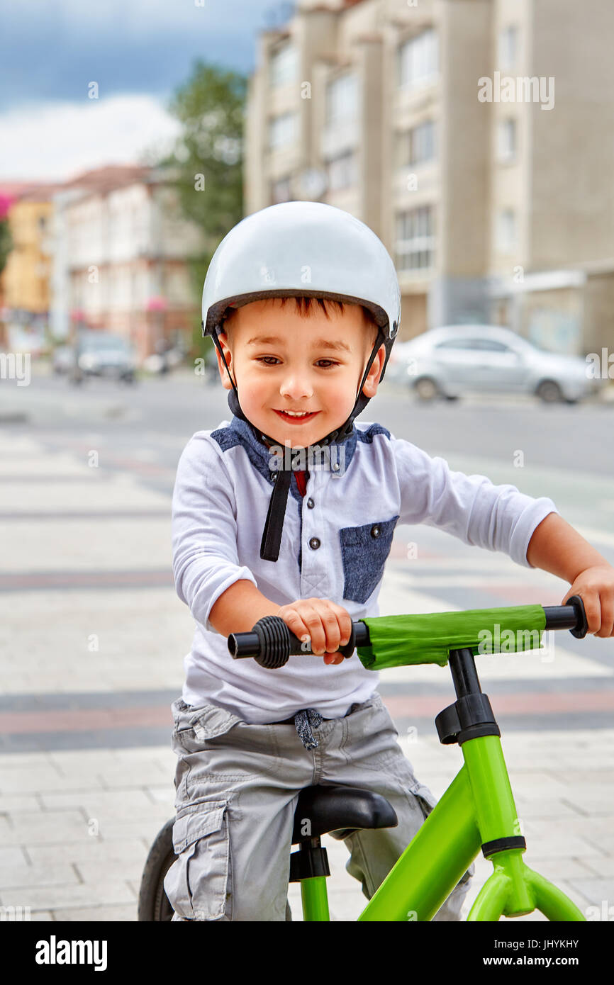 Little boy kid in helmet ride a bike in city park. Cheerful child