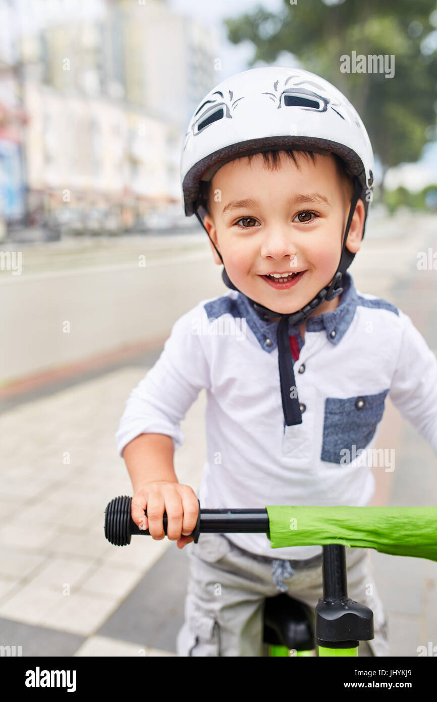 Little boy kid in helmet ride a bike in city park. Cheerful child