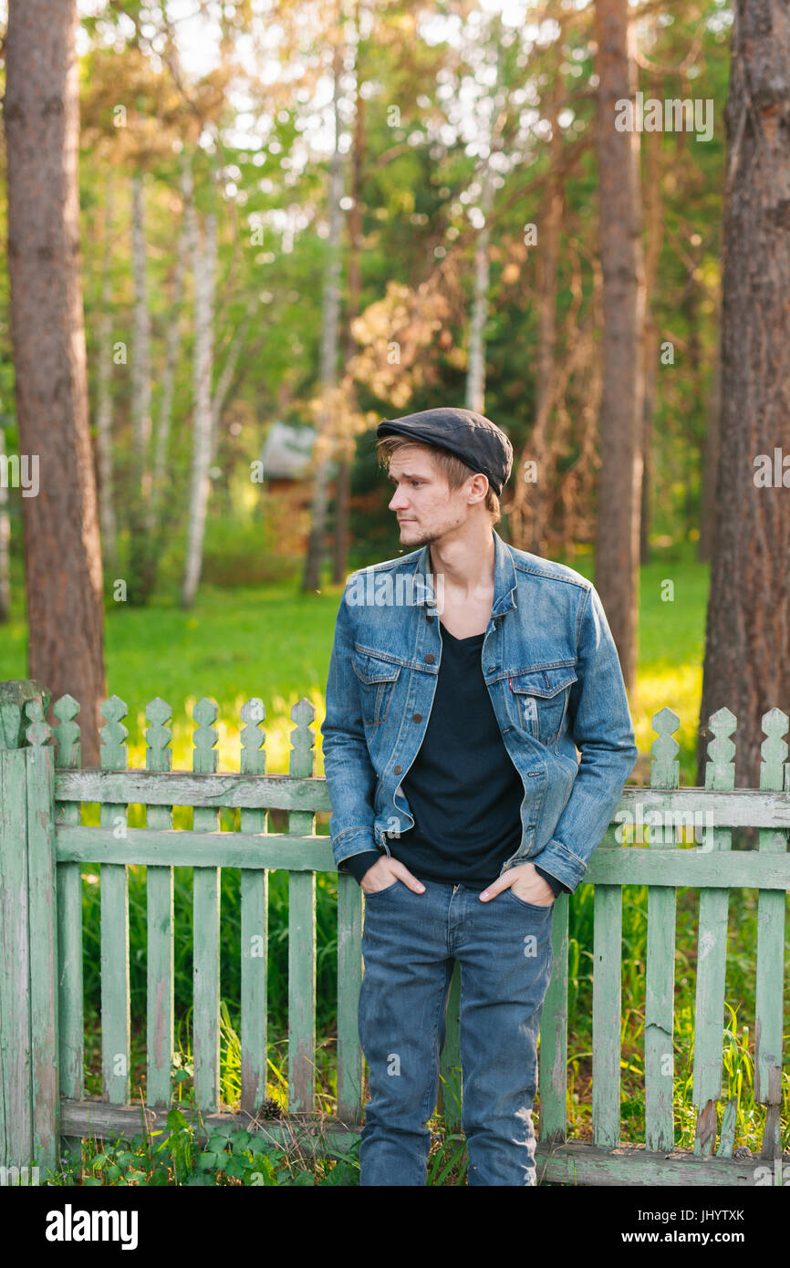 Retro-styled young man. He is leaning on a fence. Stock Photo