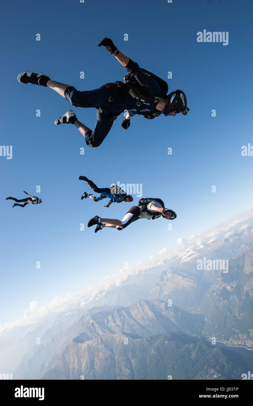 Four skydivers lining up on a tracking jump above Locarno, Switzerland with the Alps in the background Stock Photo