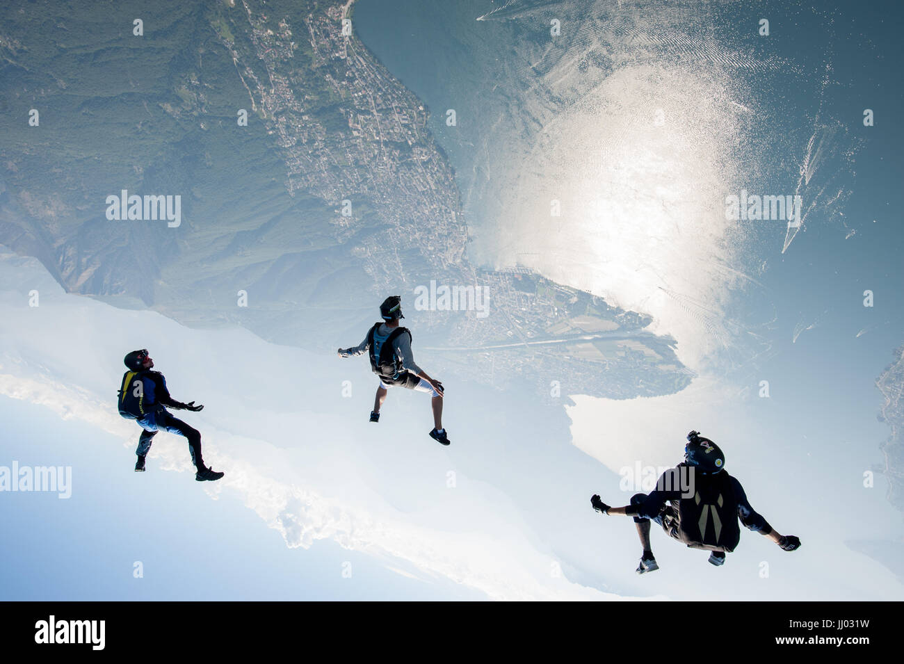 Three skydivers tracking above Locarno, Switzerland with the alps in the Background Stock Photo