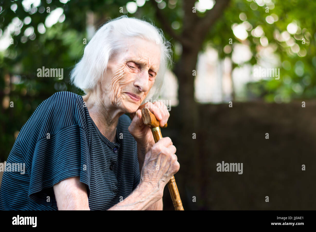 Senior woman crying with a walking cane outdoors Stock Photo